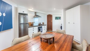A modern kitchen with white cabinetry, a stainless steel refrigerator, and a wooden dining table with six chairs.