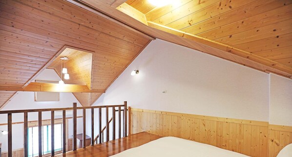 A high-ceilinged room with wooden beams, a sloped ceiling, and a wooden staircase leading to an upper level. - Baili Manor Cing Jing (Ren'ai)