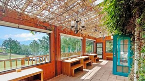 A wooden deck with benches and tables, large windows, and a view of trees and mountains. - Baili Manor Cing Jing (Ren'ai)