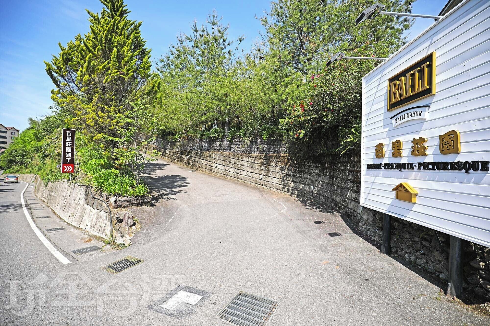 A pathway leading to a building with a sign reading "Baili Manor" and "Baili Manor Picture House".