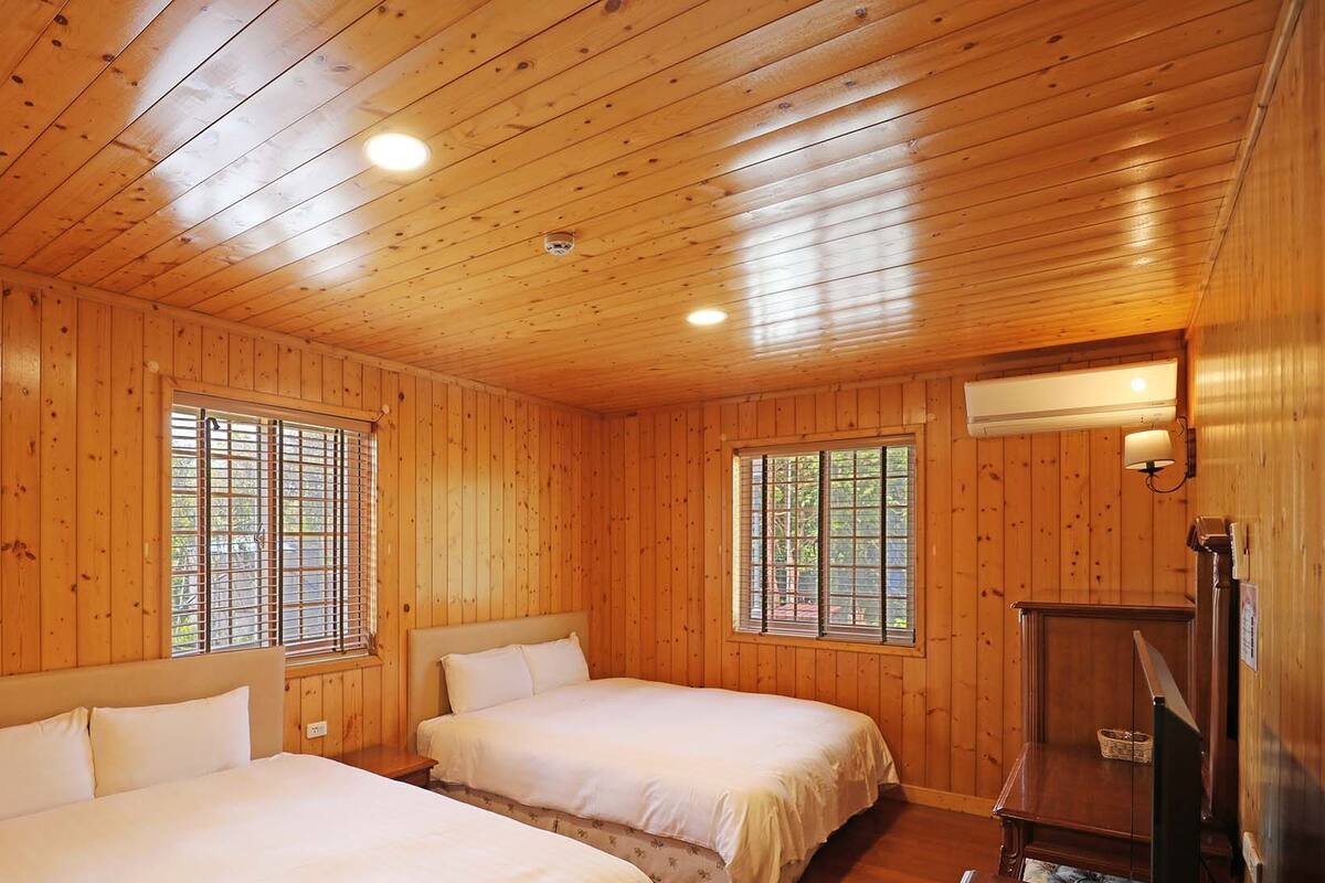 A cabin with two beds, wooden walls, and a ceiling with wooden beams.