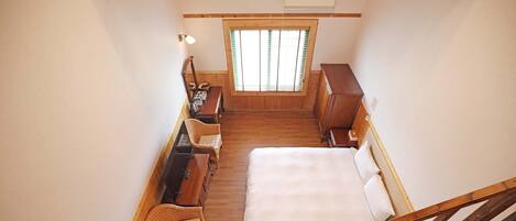 A bedroom with a bed, wooden furniture, a desk, and a window with blinds.