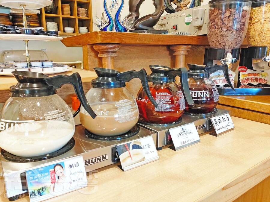 A coffee station with various brewing equipment and labeled tea options.