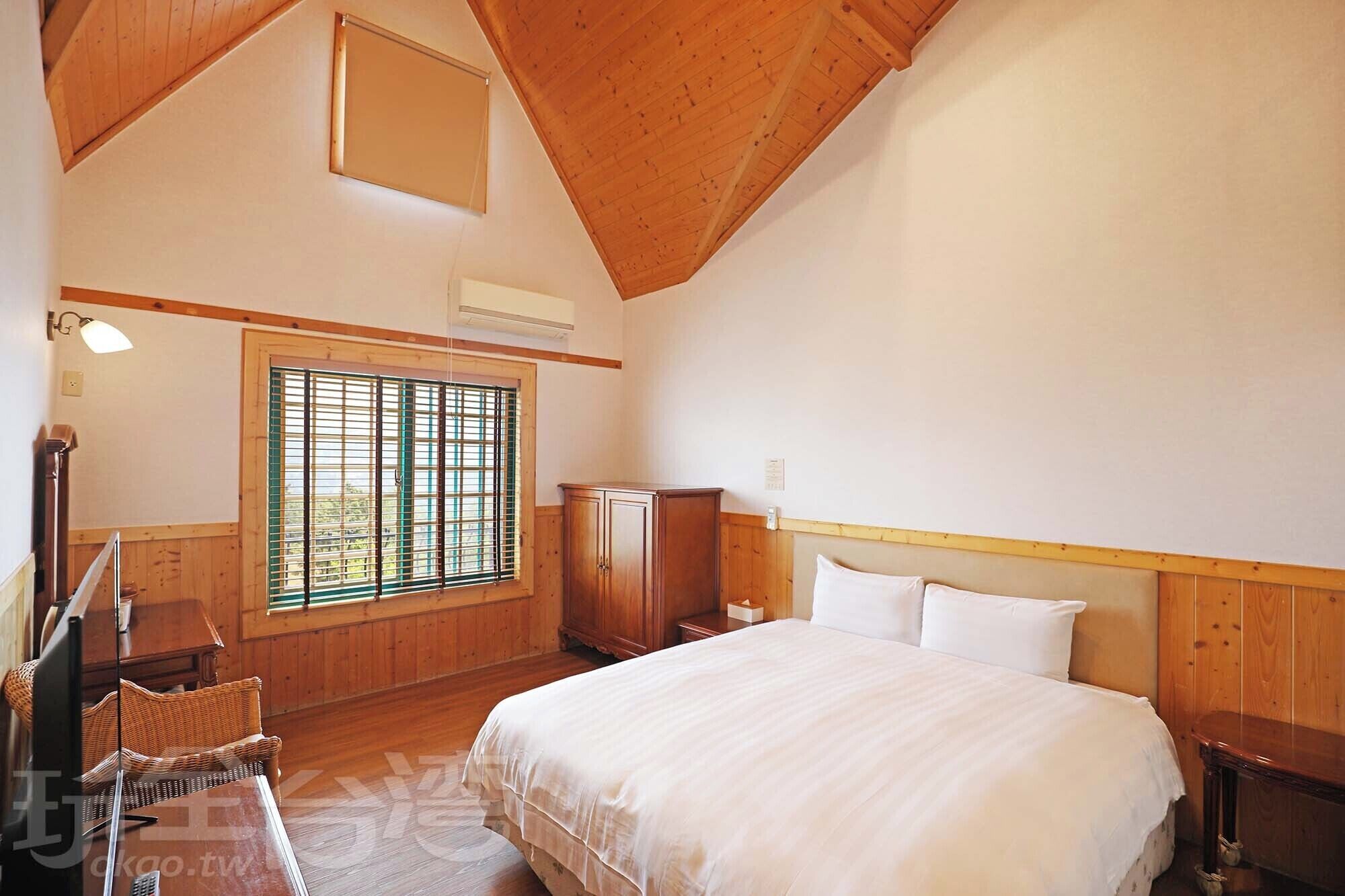Un dormitorio con una cama grande, paredes de madera, una ventana con persianas, un escritorio y una silla.