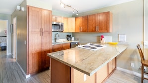 A modern kitchen with wooden cabinets, a stainless steel microwave, a gas stove, and a granite countertop.