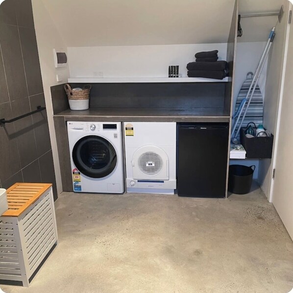 Une petite buanderie équipée d’un lave-linge, d’un sèche-linge et d’un petit réfrigérateur.