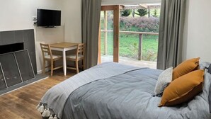 Une chambre à coucher avec un lit, une télévision, un bureau et une vue sur l’extérieur.