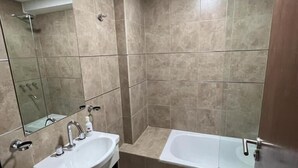 Une salle de bain avec un lavabo, un miroir et une baignoire.