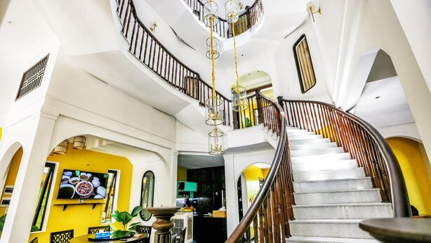 A grand staircase with a wooden handrail and glass railings, leading to a second floor.