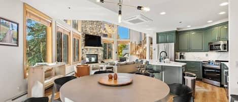 A modern kitchen with a central island, built-in appliances, and a dining area with a round table.
