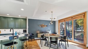 A modern kitchen with a central island, bar stools, and a dining area with chairs.