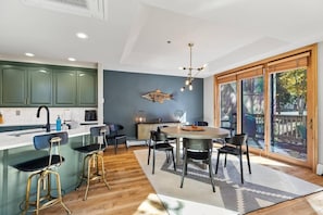 A modern kitchen with a central island, bar stools, and a dining area with a round table and chairs.