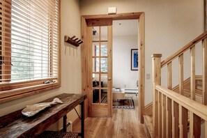 A wooden staircase with a glass door leading to a room with a bed and a rug.