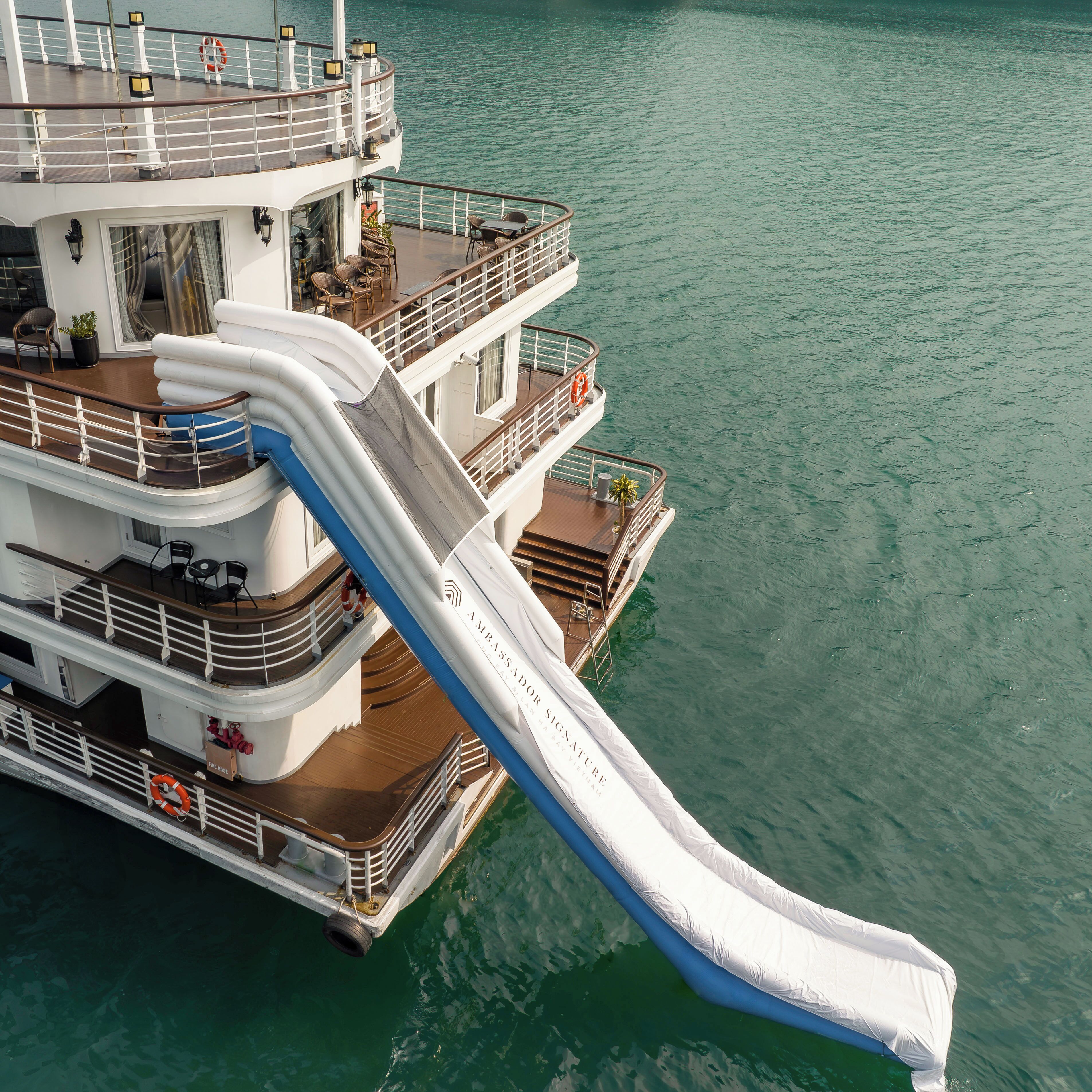 A cruise ship with a large white water slide extending from the upper deck.