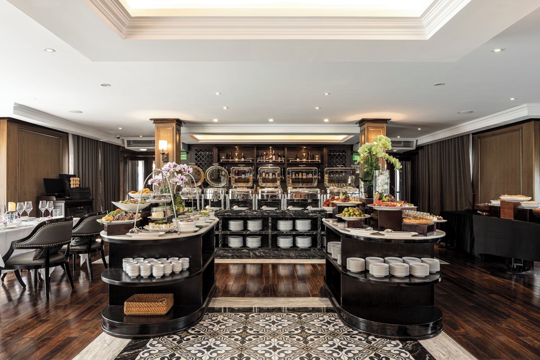 Een luxueuze hotellobby met een centraal buffetgedeelte, stijlvolle zitplaatsen en een goed gevulde bar.