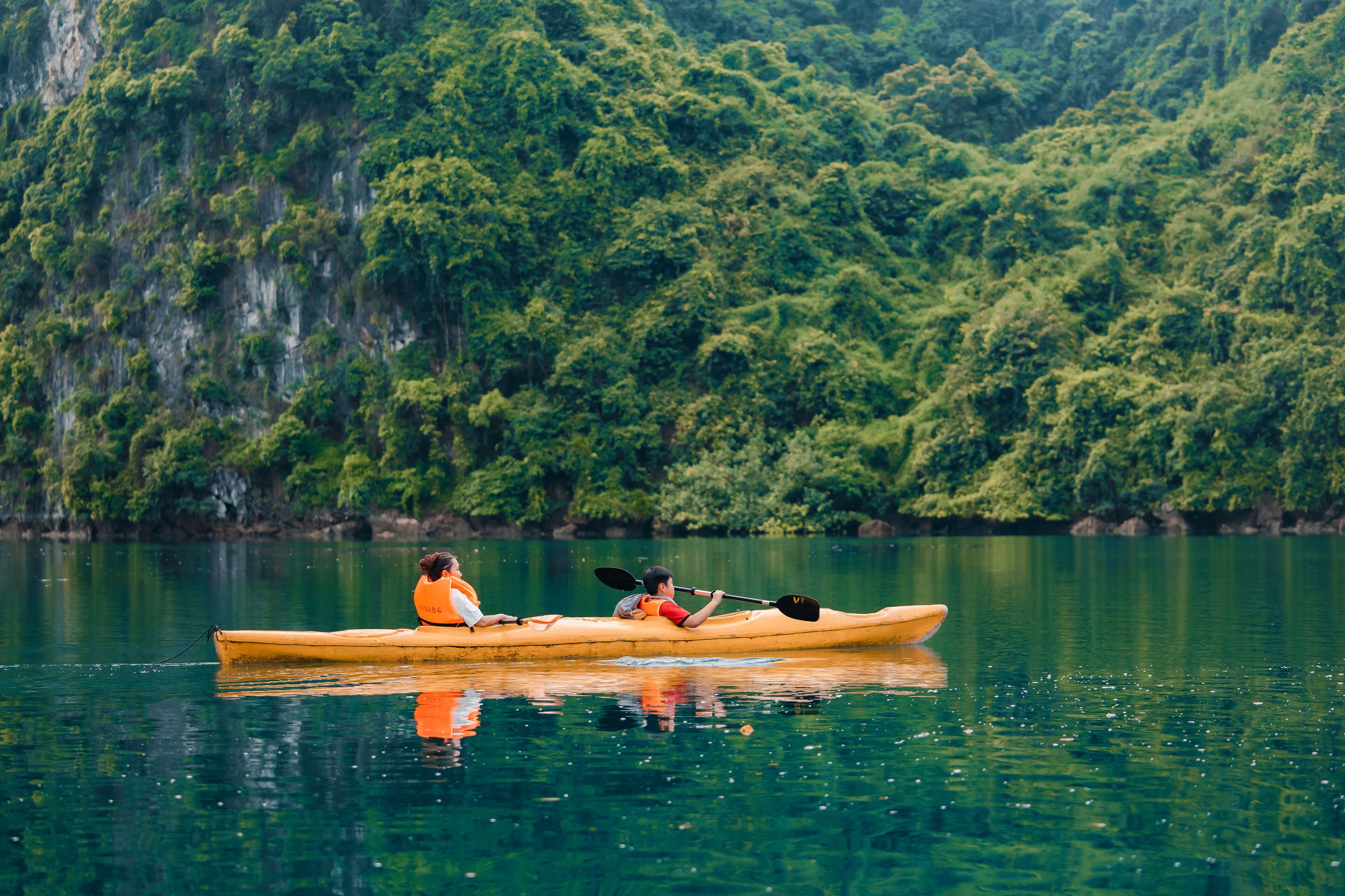 A kayak on calm water with a forested cliff in the background.
