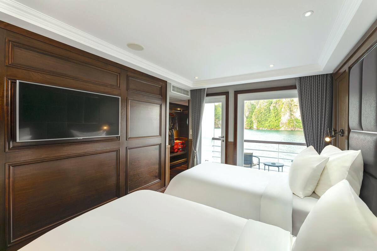 A hotel room with a large bed, a TV mounted on the wall, and a view of the outdoors.