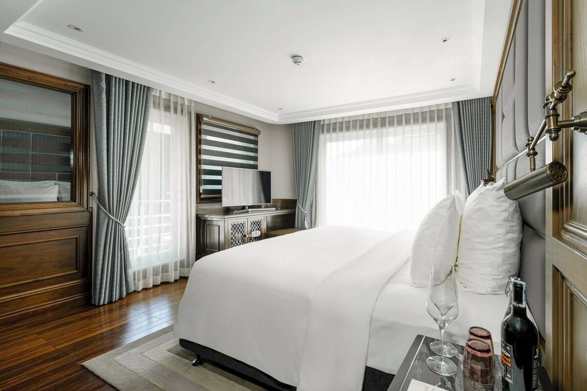 A modern hotel room with a large bed, a desk, and a bathroom with a shower.