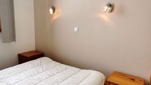 Un dormitorio con una cama, dos mesitas de noche e iluminación en la pared.