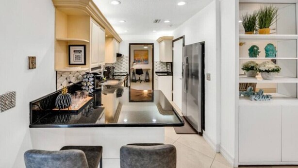 A modern kitchen with a central island, white cabinetry, and a built-in refrigerator.