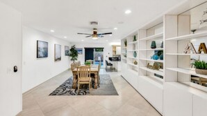 A modern interior with a dining area, white shelving units, and a ceiling fan.