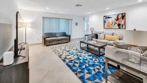 A modern living room with a sofa, coffee table, and a patterned rug.