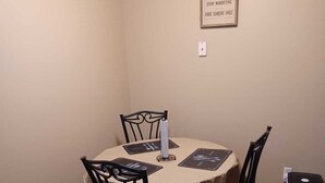 Un petit coin repas avec une table ronde, deux chaises et une citation inspirante encadrée au mur.