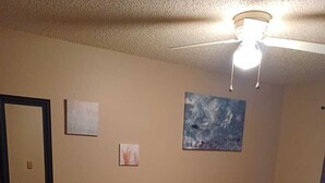 Une chambre comprenant un lit, un bureau, une chaise, un tapis et deux œuvres d’art mural.