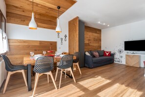 Un salon moderne comprenant un coin repas, un plafond en bois et un téléviseur à écran plat.