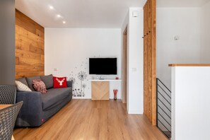 Un salon moderne avec un canapé, un téléviseur et un plancher en bois.