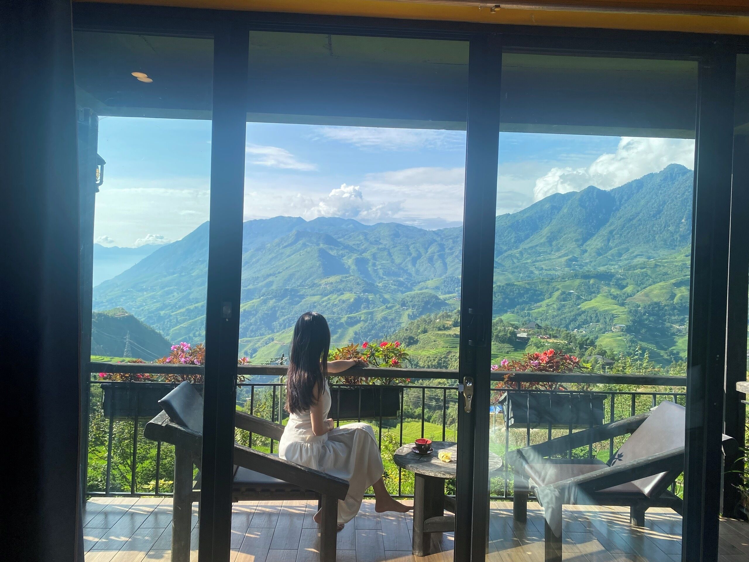 Un balcon offrant une vue sur des montagnes verdoyantes et un ciel dégagé.