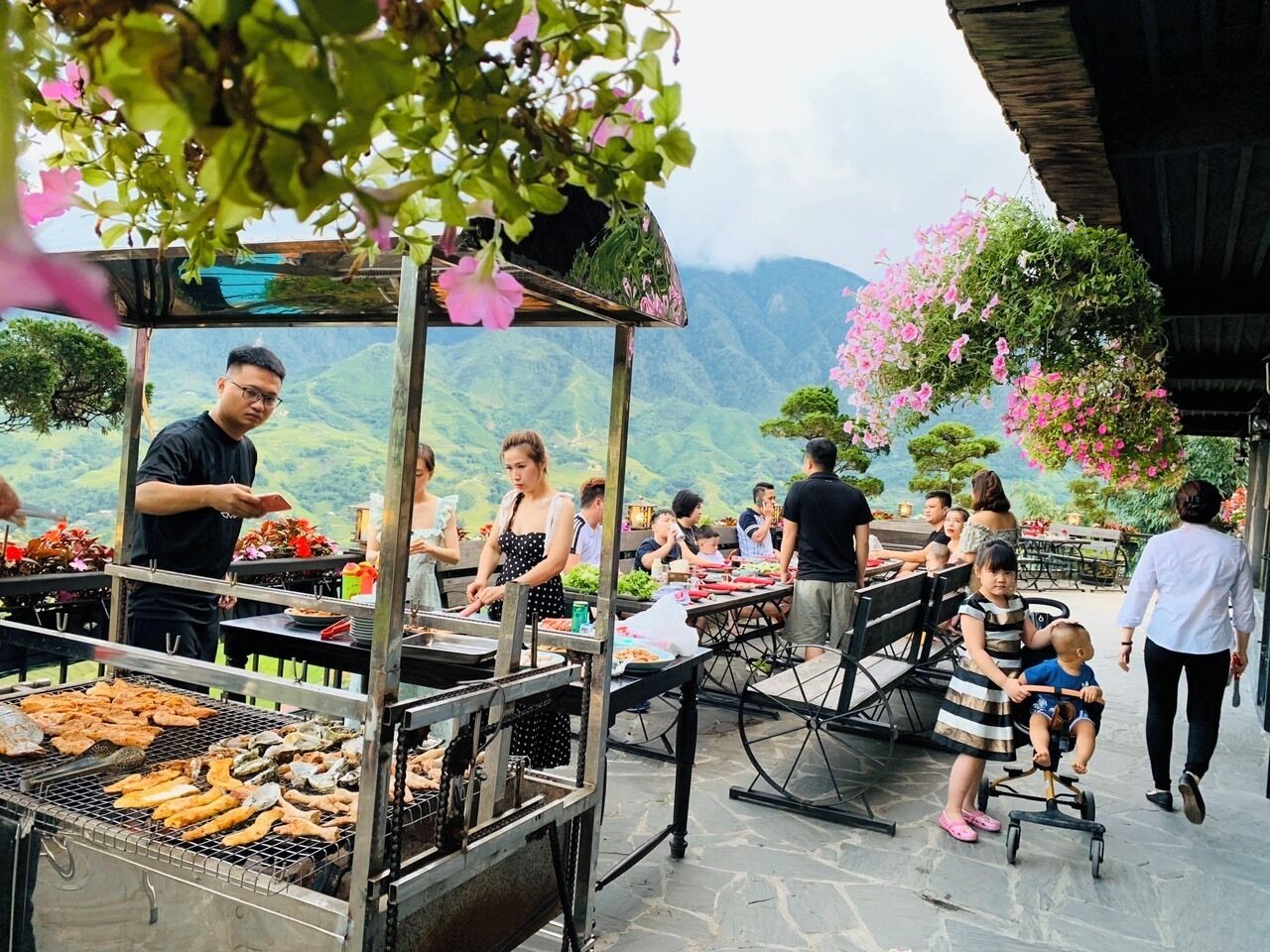 Ein Essbereich im Freien mit Grillstation und Gästen.
