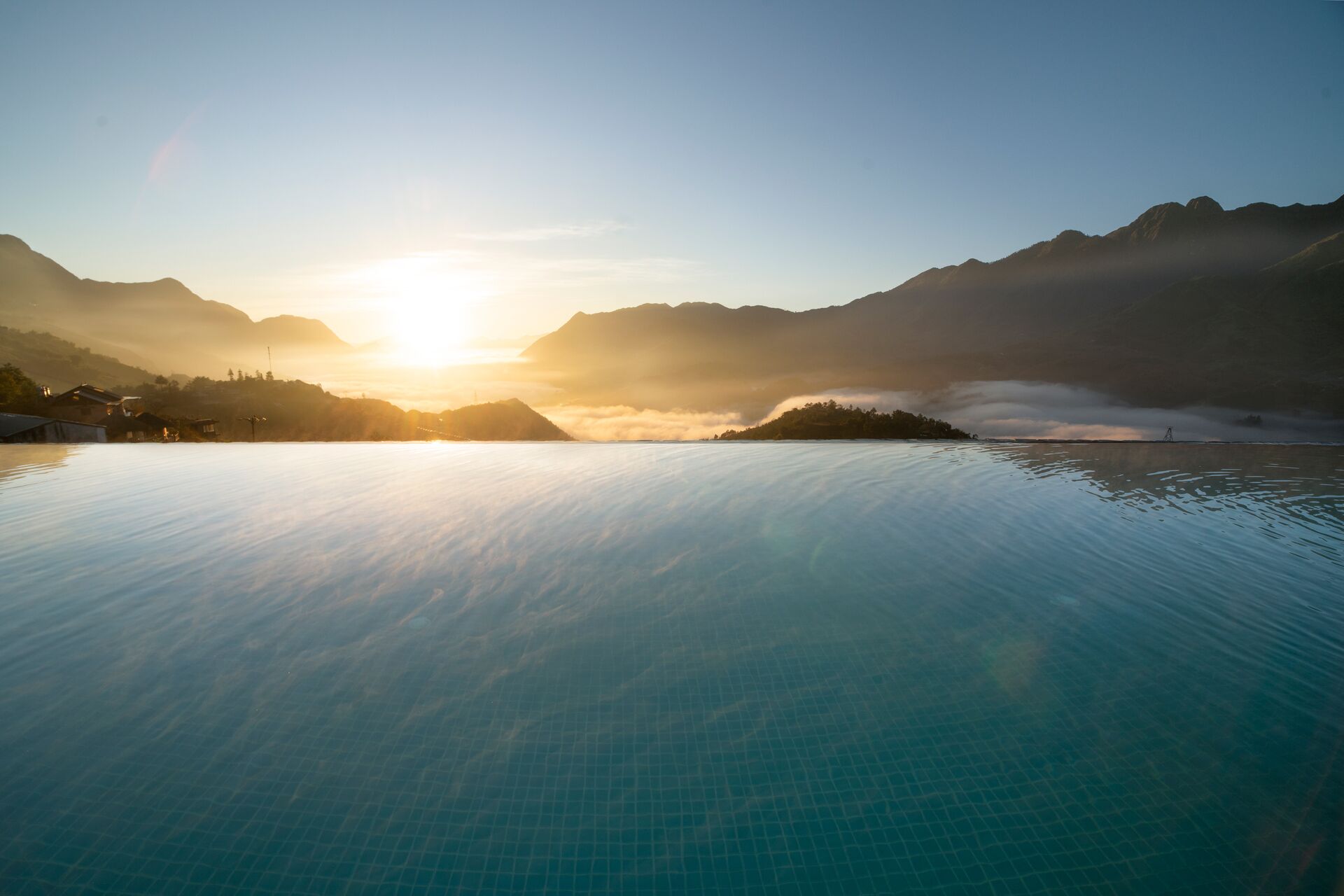 A calm lake with mountains in the background and a clear sky.