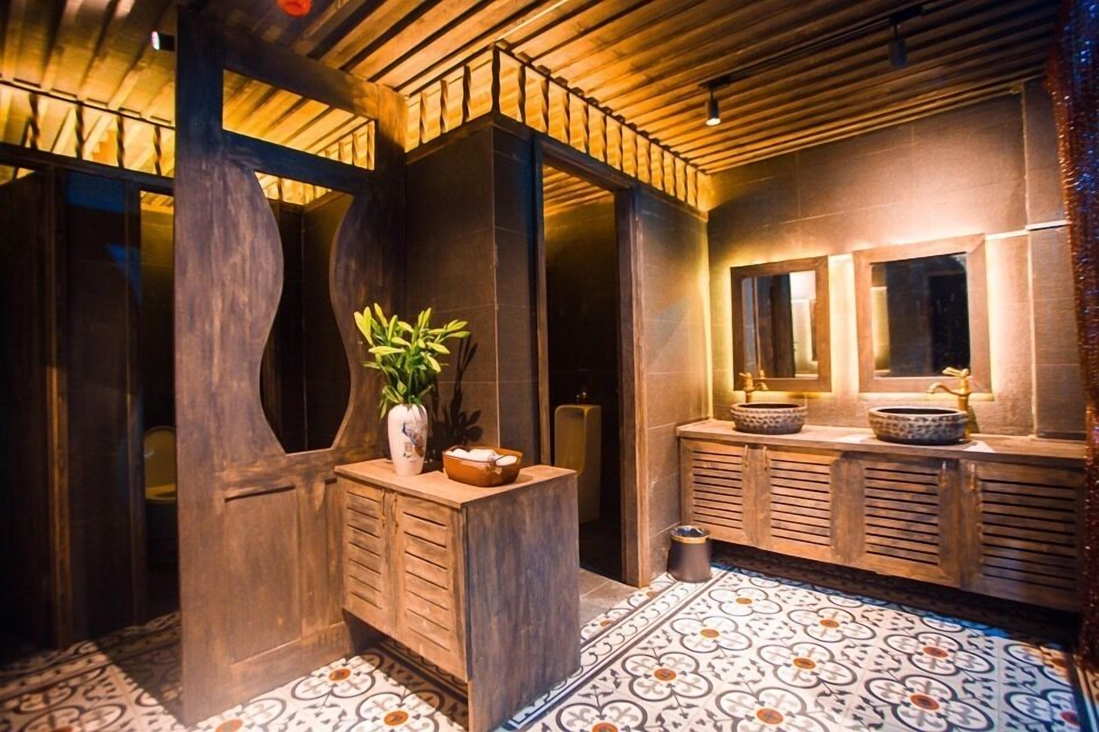 A modern bathroom with a wooden vanity, a potted plant, and a large mirror.