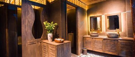 A modern bathroom with a wooden vanity, a potted plant, and a large mirror.