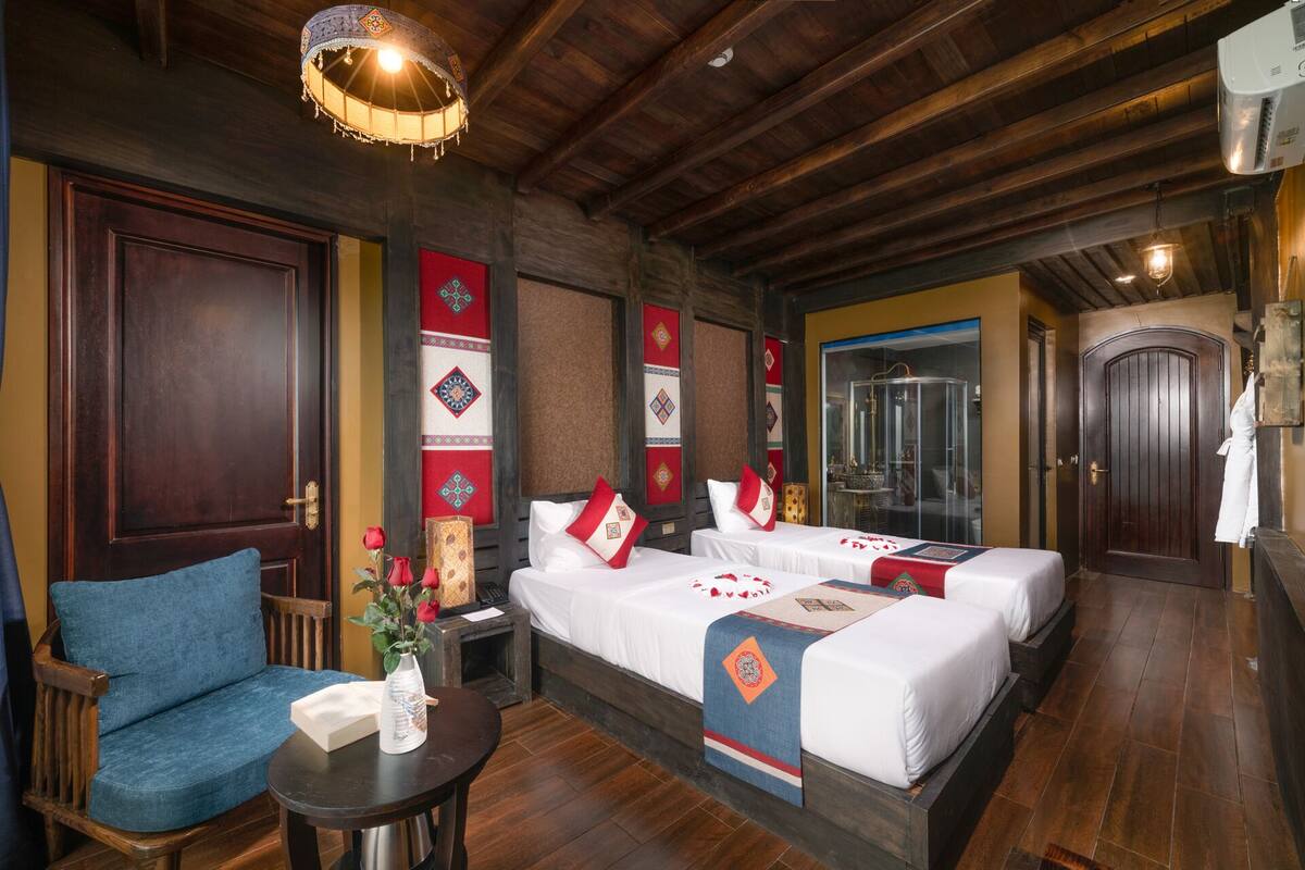A hotel room with two beds, a wooden ceiling, and traditional decor.
