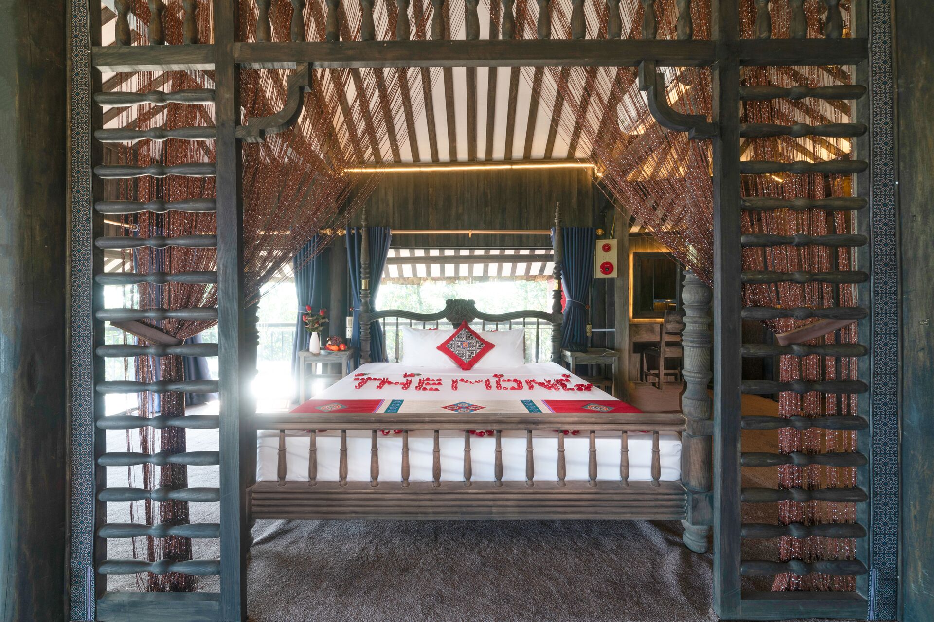 A traditional room with a bed, curtains, and a decorative wooden frame.