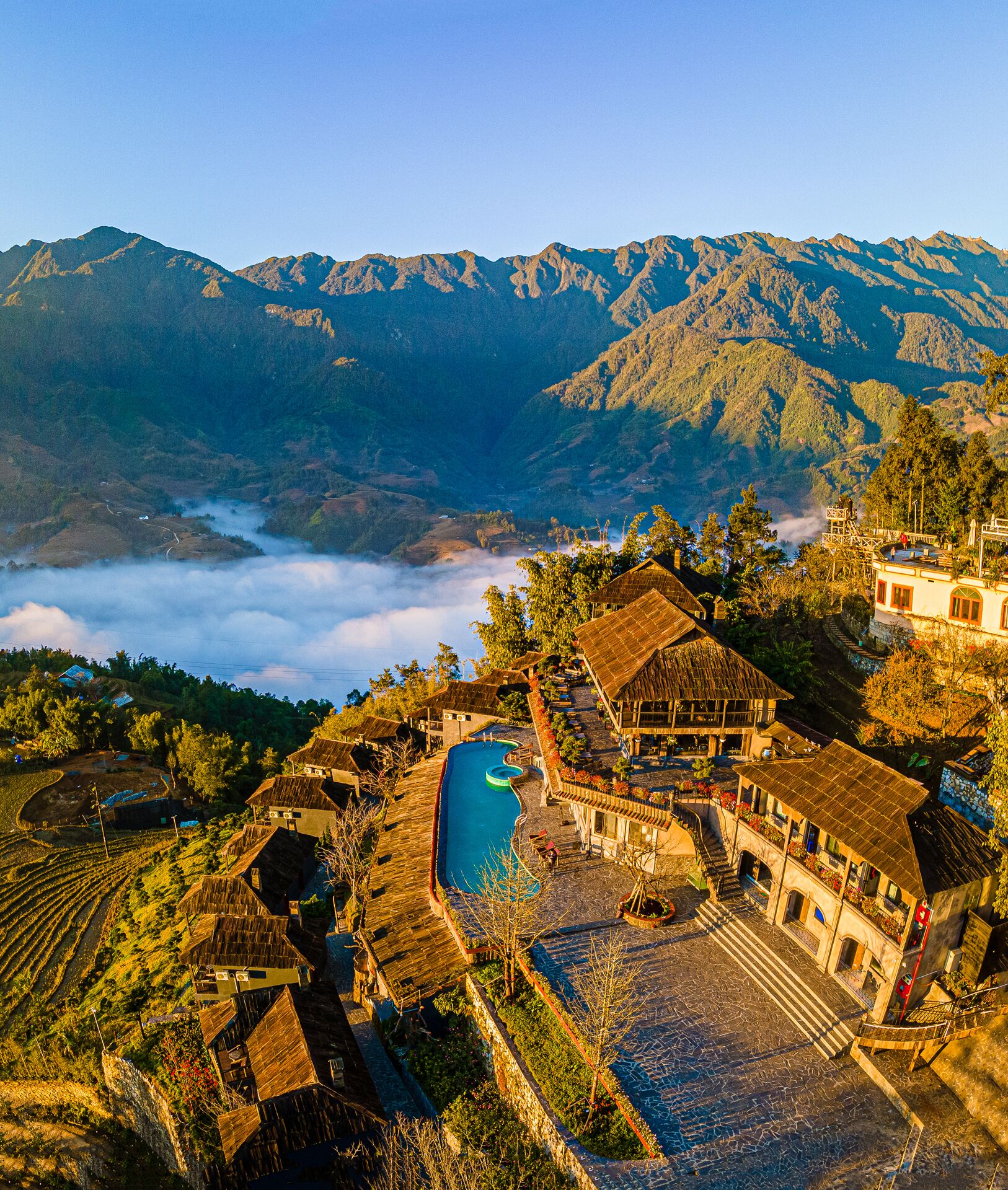 A traditional village with terraced fields, a swimming pool, and mountain views.