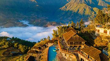 A traditional village with terraced fields, a swimming pool, and mountain views.