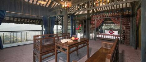 A room with a wooden table, two chairs, a sofa, and a large window overlooking a scenic view.