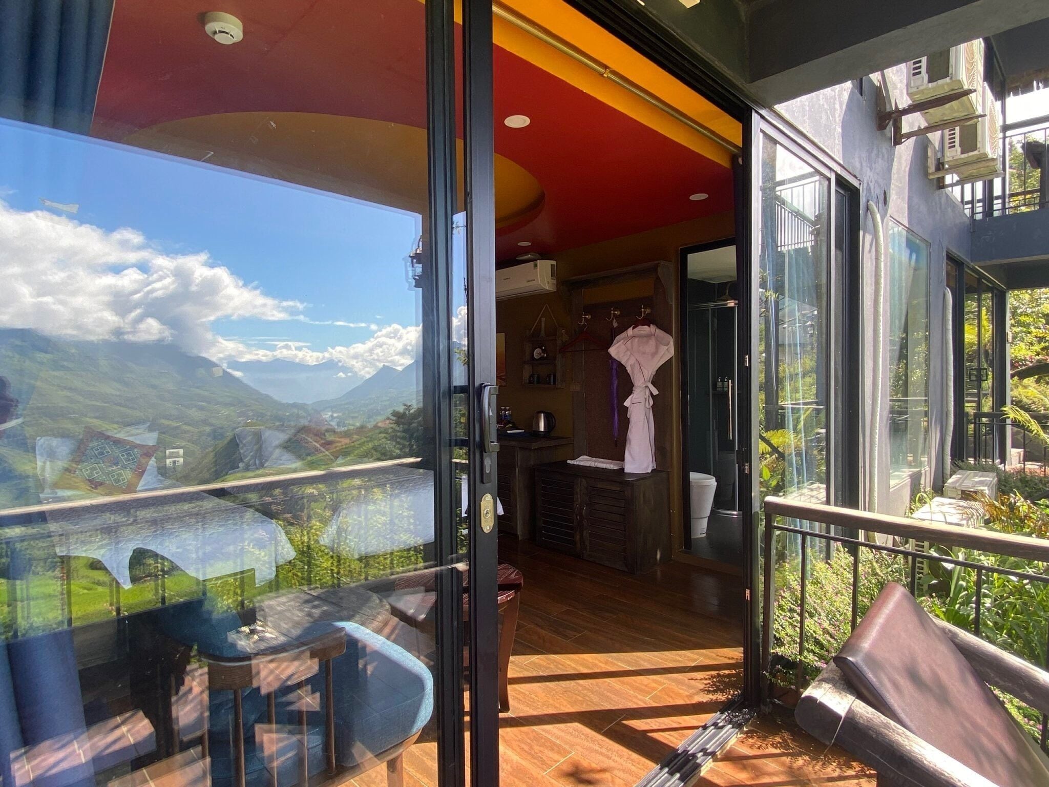 Een modern interieur met een glazen deur naar een balkon met uitzicht op bergen.