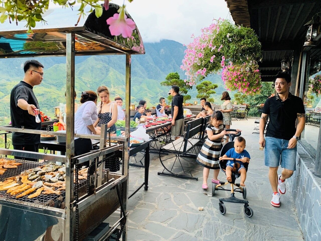 An outdoor dining area with a grill, tables, and people.