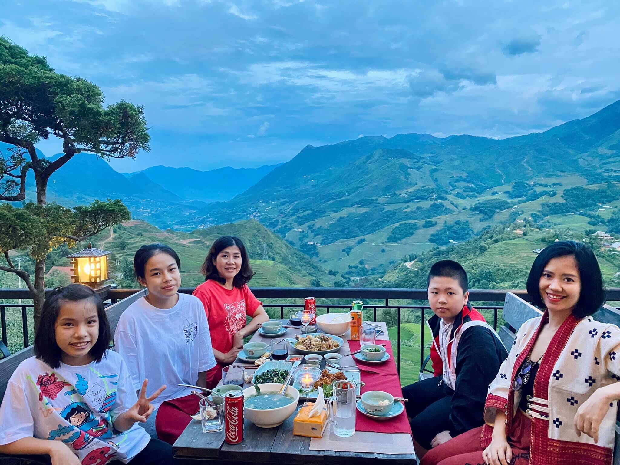 A group of people dining at a table with a scenic mountain view in the background.