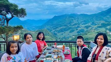 A group of people dining at a table with a scenic mountain view in the background.