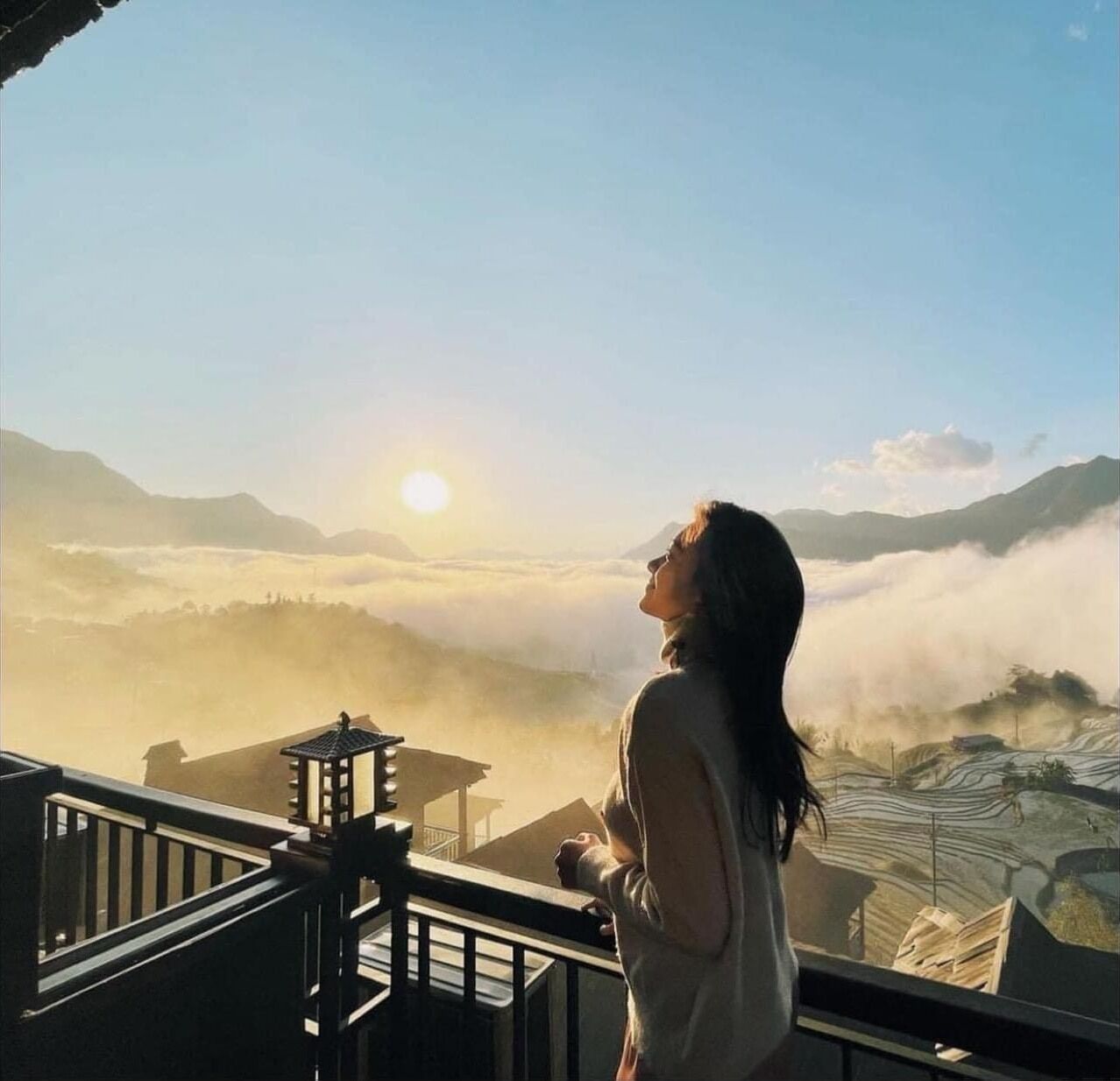 A person overlooking a mountainous landscape with a sunrise.