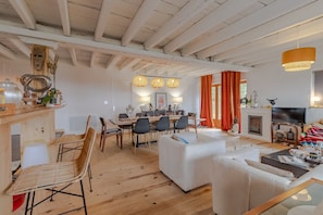 Un amplio salón con mesa de comedor, sofás y chimenea.