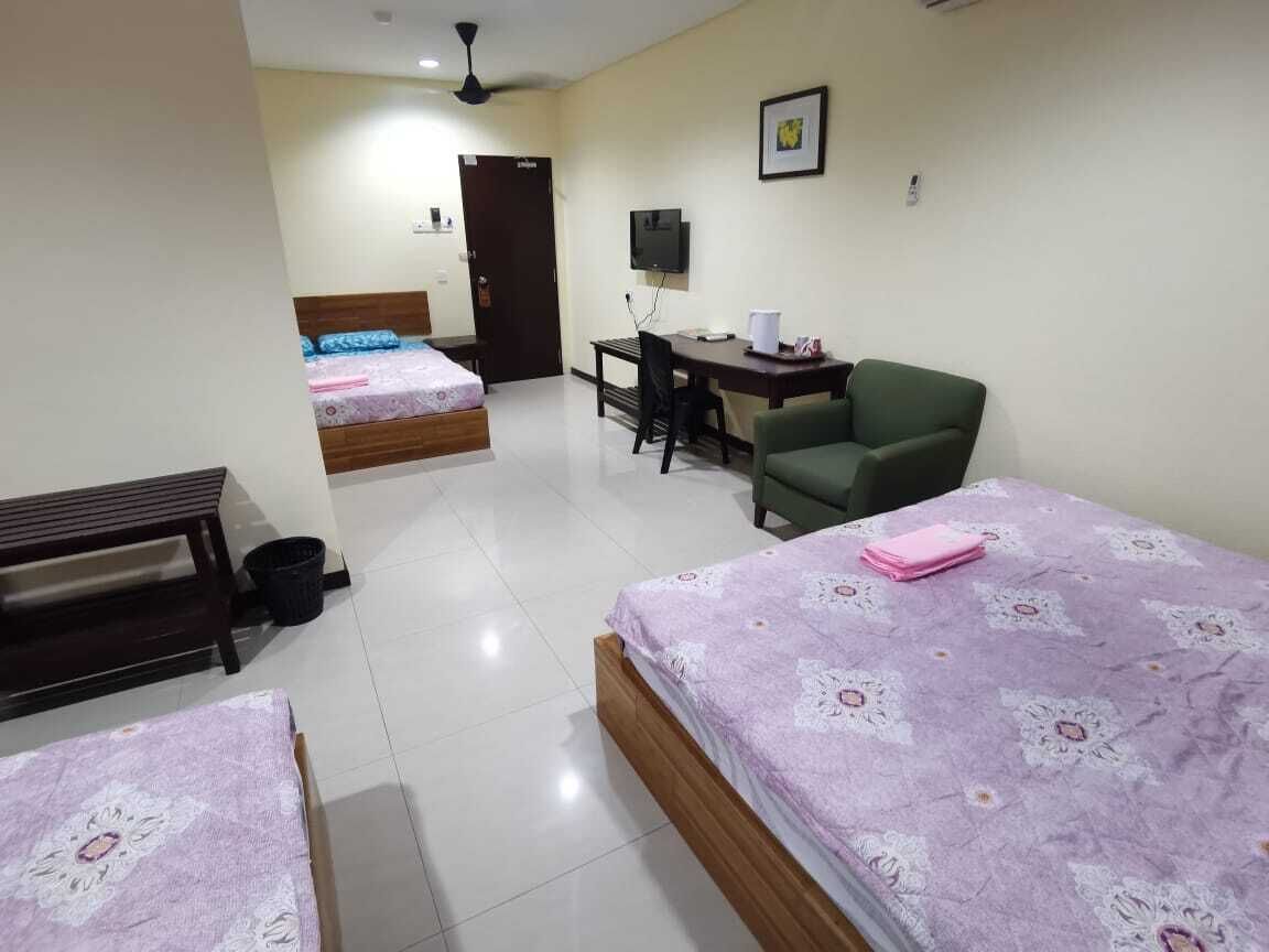 A hotel room with two beds, a desk, a chair, and a television.