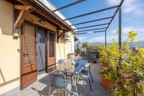 A patio with a table and chairs, a wooden door, and a view of the cityscape.