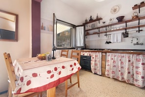 Una cucina con tavolo da pranzo, sedie, una finestra e diversi utensili ed elettrodomestici.