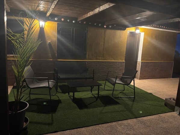 An outdoor patio with a table and chairs, a potted plant, and a wall with a light fixture. - Vacation Rental 'Apartamento Brownie' with Sea View, Private Terrace and Wi-Fi (Firgas)